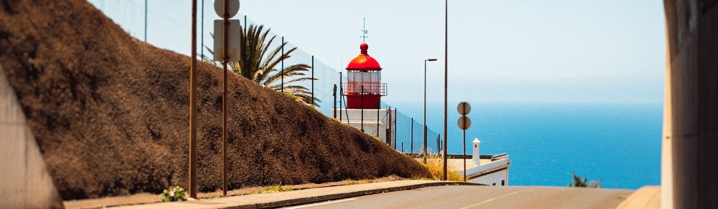A winding coastal path leading to a red lighthouse