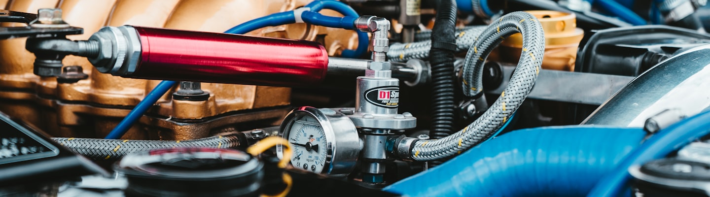Colorful engine of a classic car, with blue hoses and a red damper